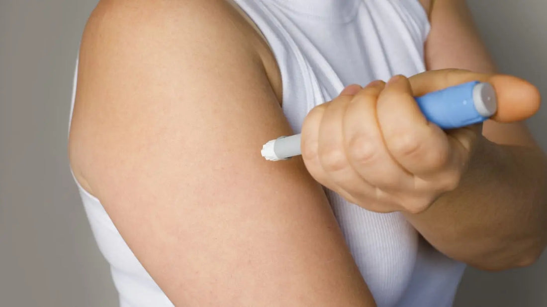 Frau setzt sich Spritze in den Oberarm